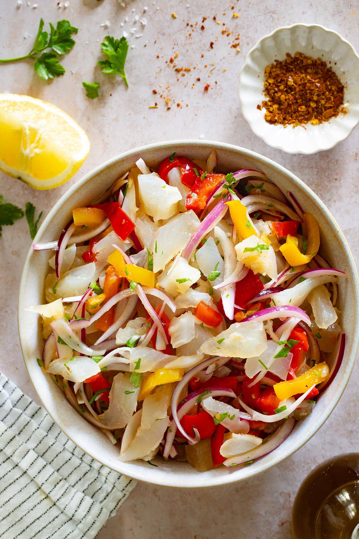 Insalata di nervetti in a bowl with a lemon wedge and peperoncino powder in small bowl on the side.