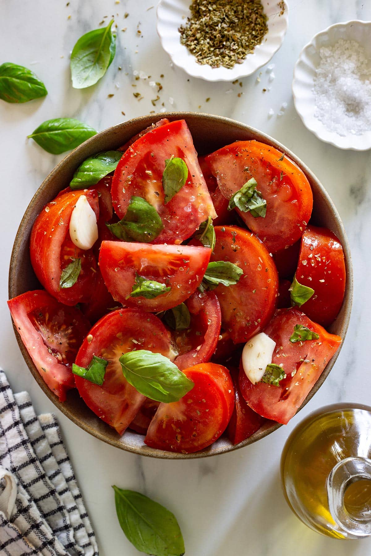 Insalata di Pomodori in a bowl with some ingredients scattered around.