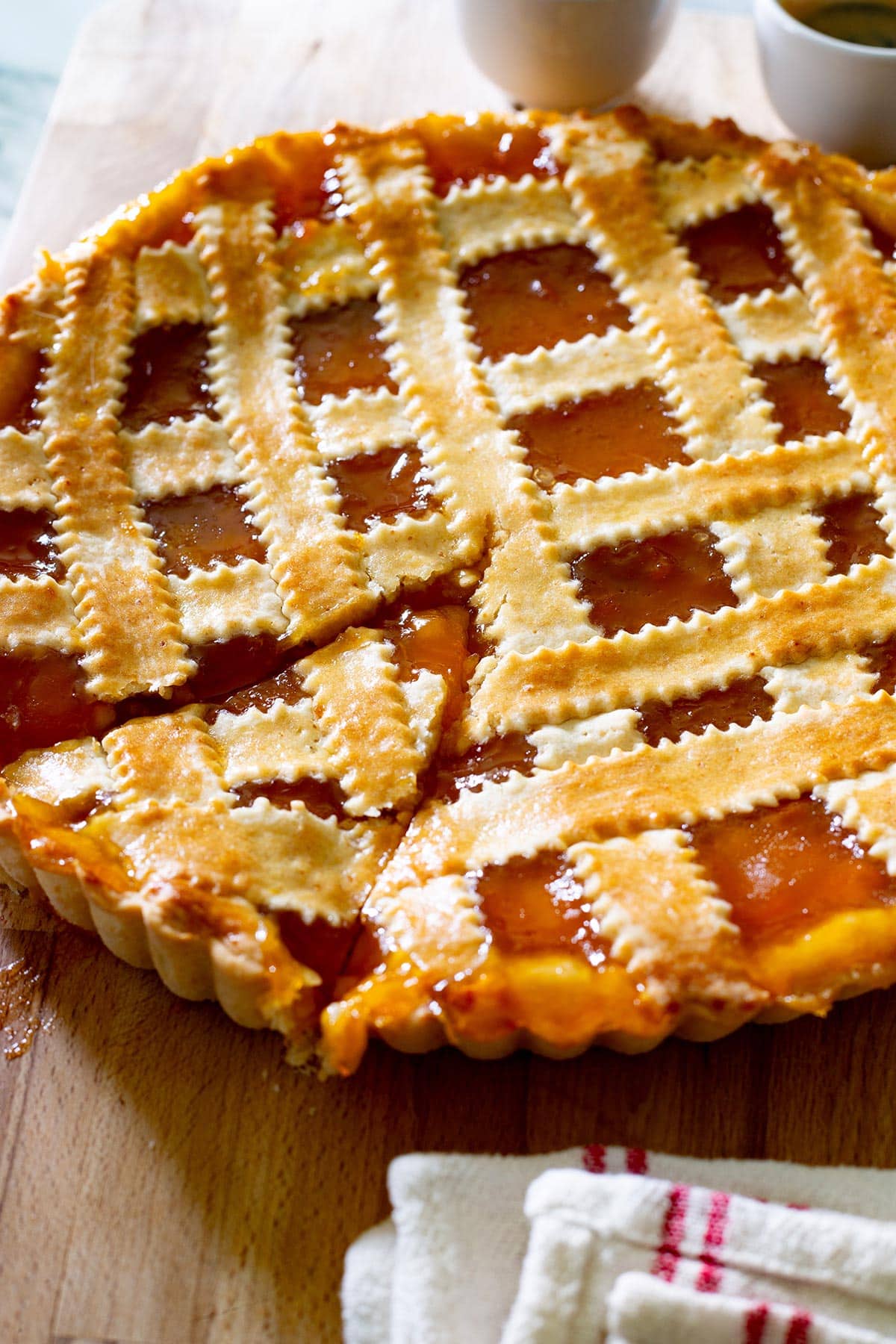 Italian crostata di marmellata on a wooden cutting board.