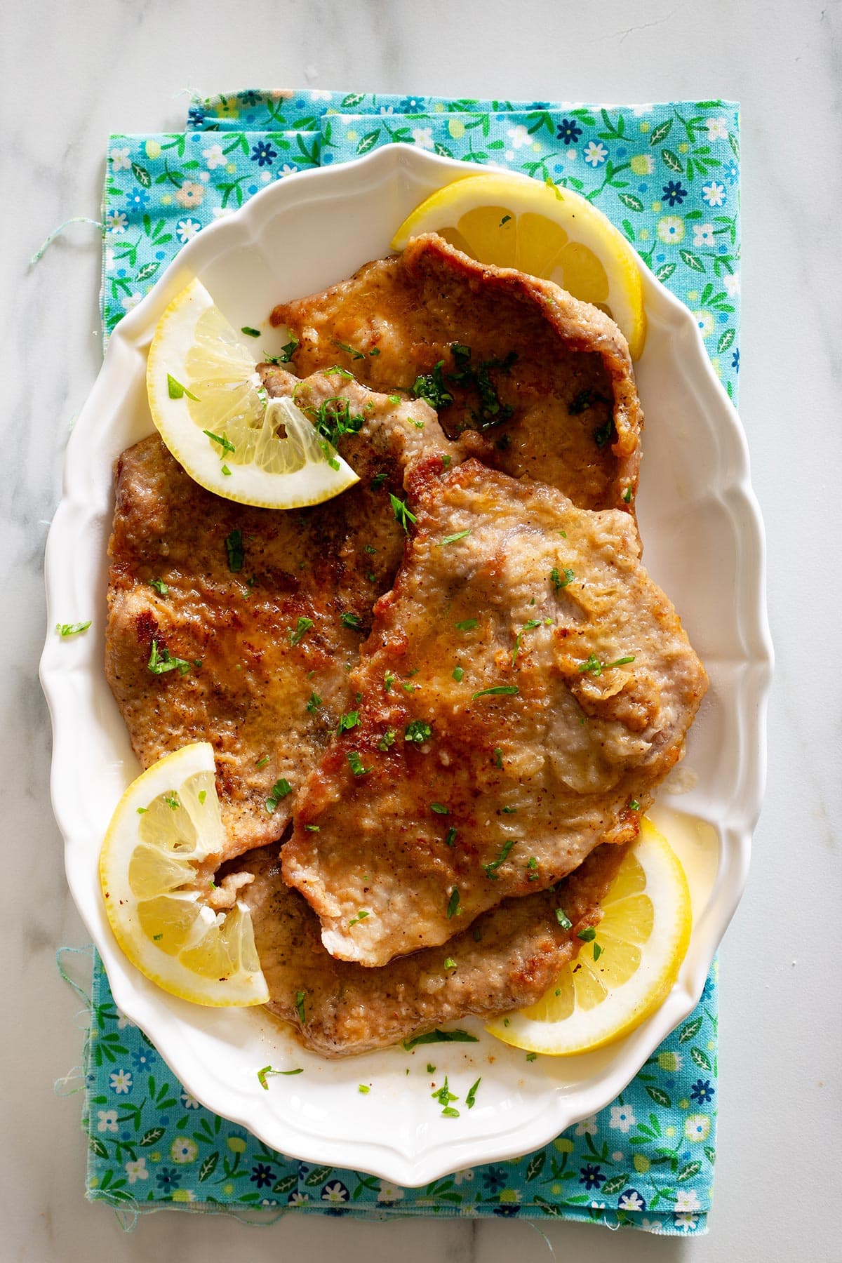 Scaloppine al limone on a serving plate garnished with parsley and lemon slices.