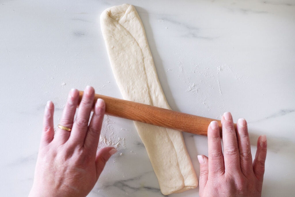 Flattening the dough with a rolling pin.