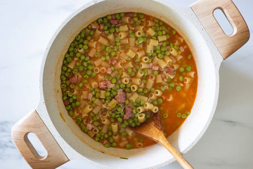 Fully cooked pasta e piselli in a pot.