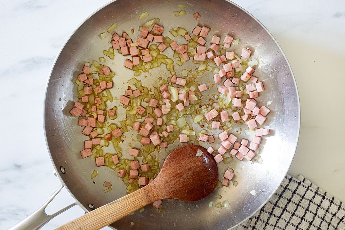 Cooking onion and ham in a pan.