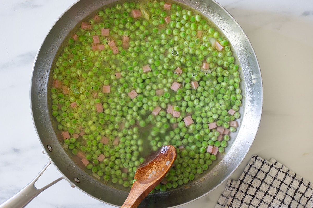 Water added to the pan with peas and ham.