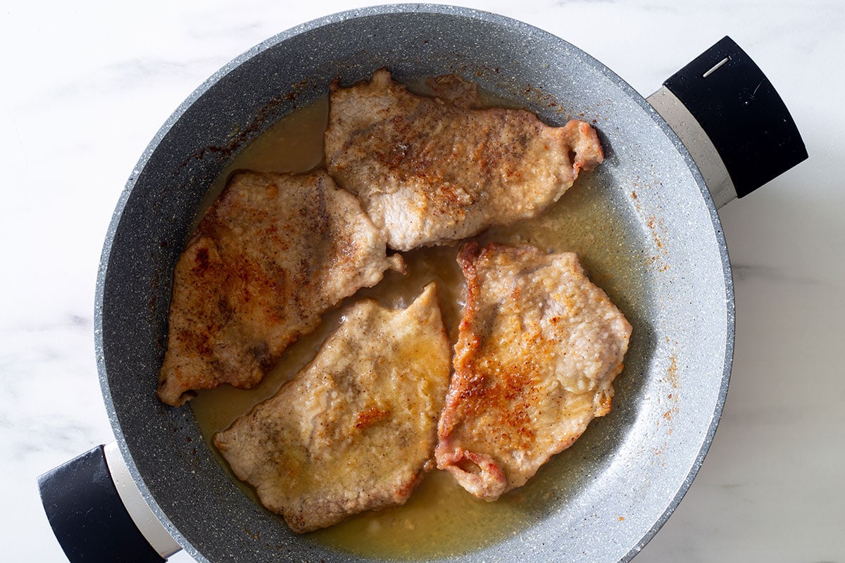 Veal scaloppine with the lemon sauce cooking on a pan.