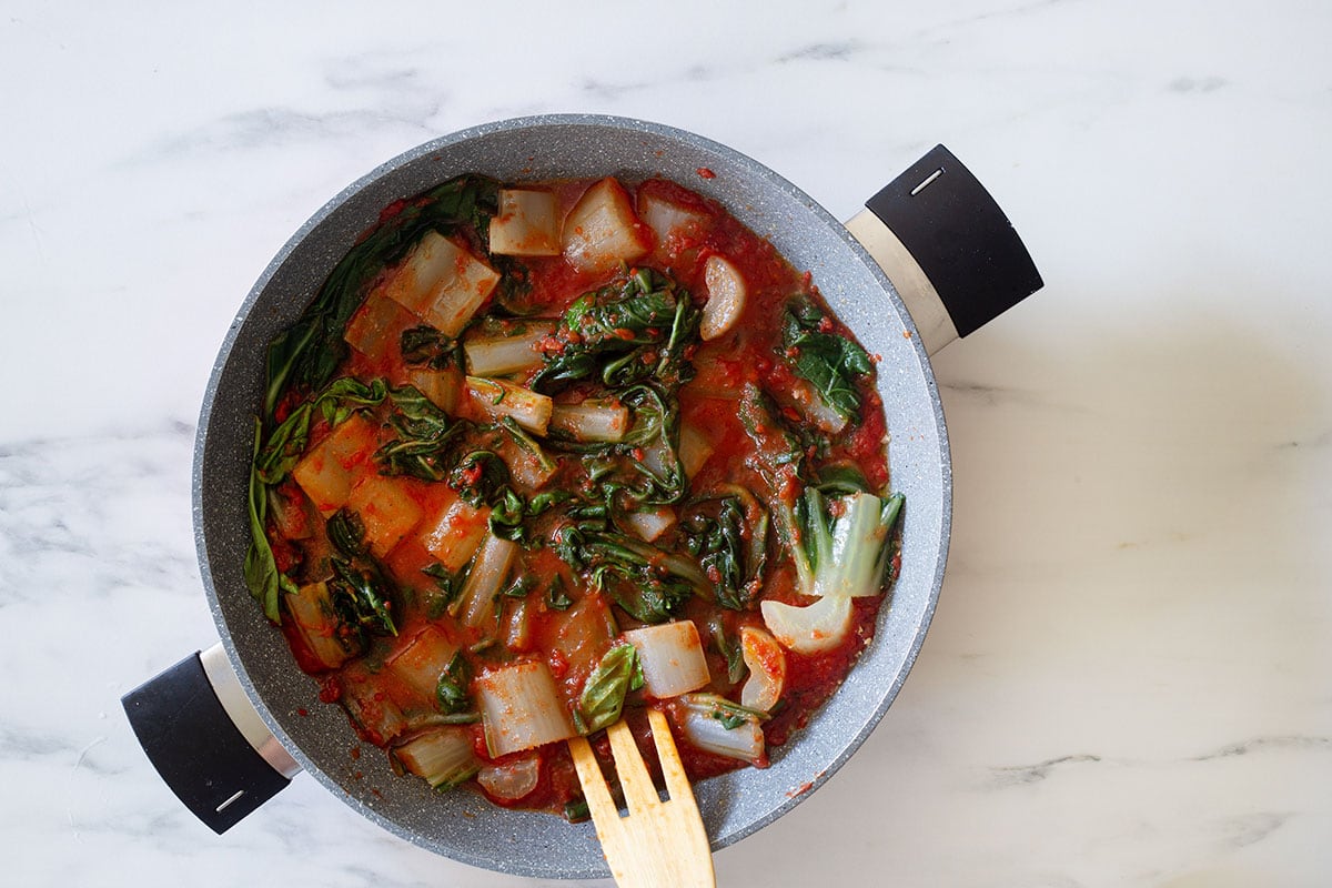 Cooking chard and tomato sauce in a pan.
