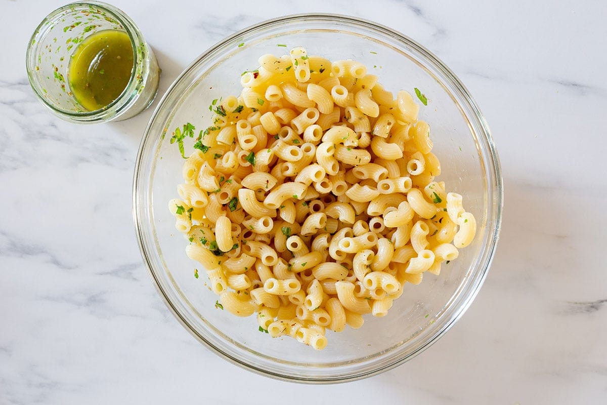 Cooked pasta in a bowl mixed with some dressing.