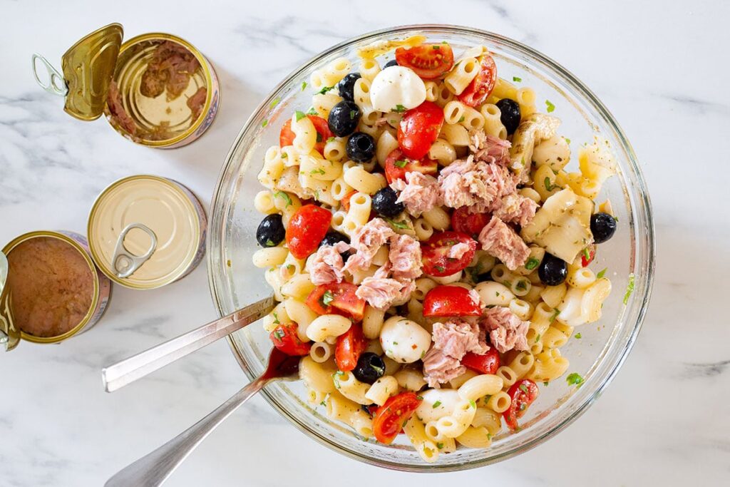 Tuna added to the bowl with pasta and other ingredients.