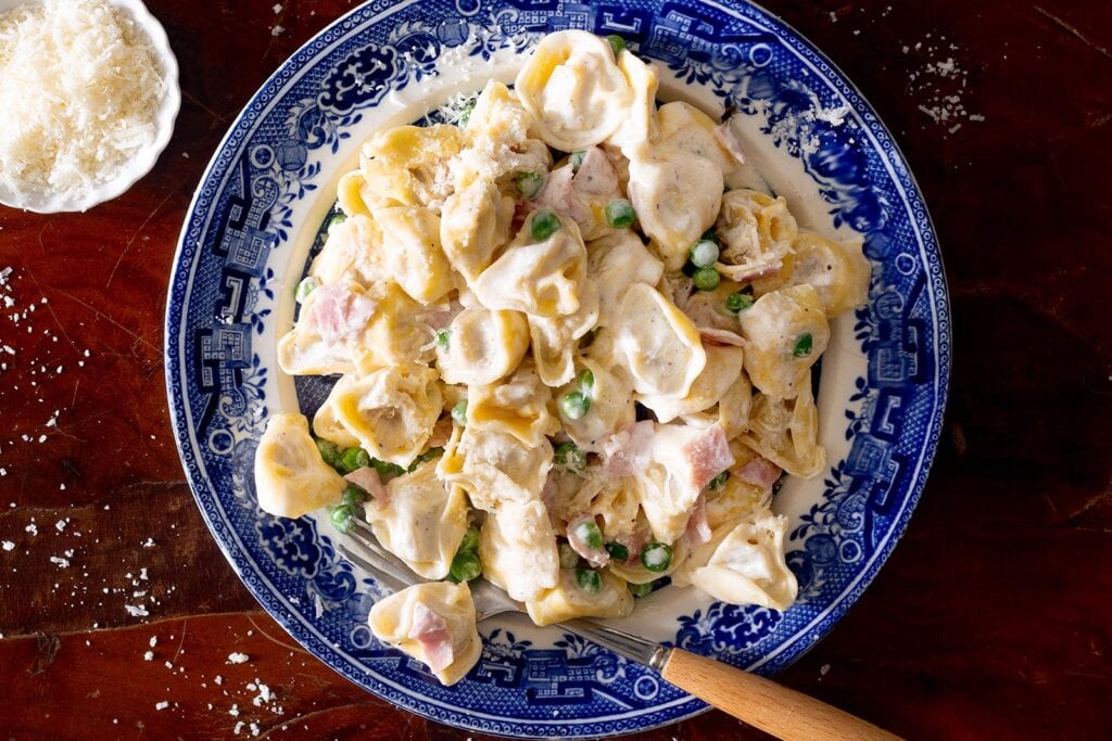 Tortellini alla panna in a plate with a fork.