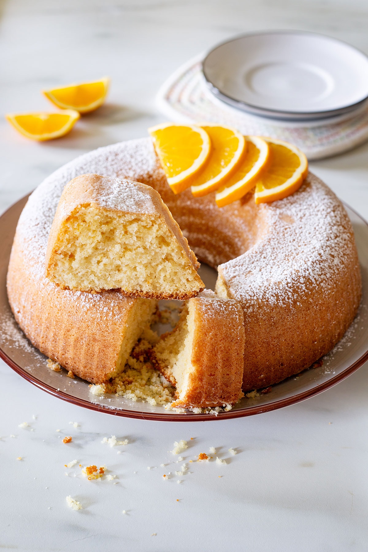 Ciambella all'arancia on a platter with a portion sliced.
