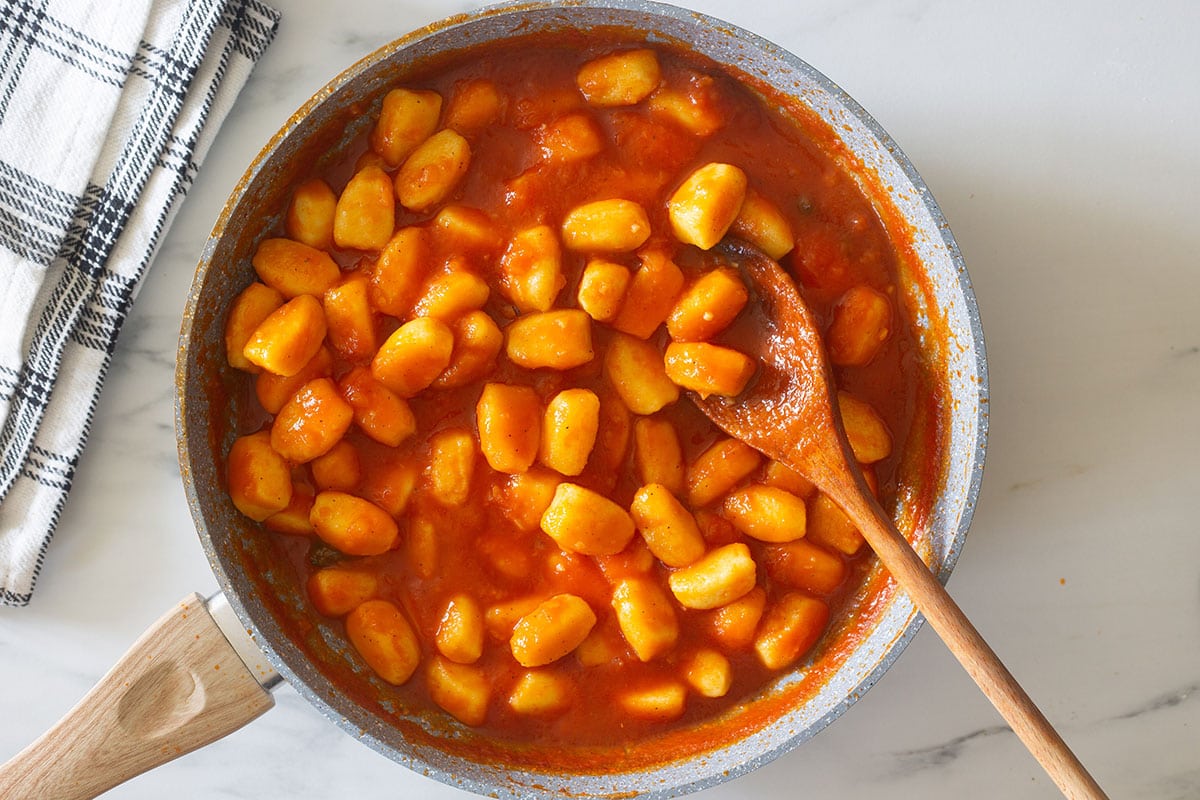 Gnocchi coated in the tomato sauce, in a pan.