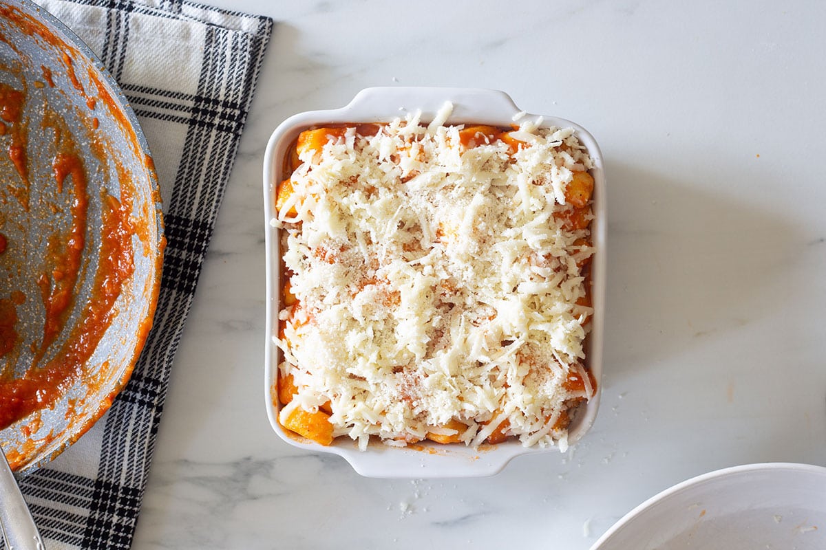 Gnocchi with tomato sauce in a pan, topped with cheese.